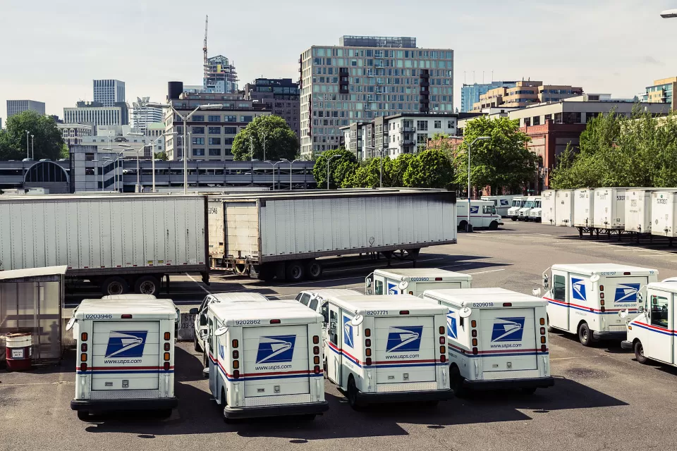 Mail delivery trucks in the parking lot at the United States Postal Service (USPS) main post office and distribution facility at 715 NW Hoyt Street in Portland, Oregon.